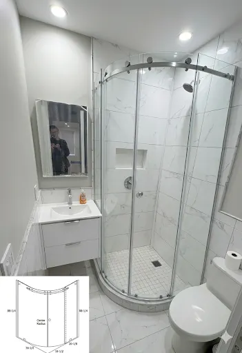 Neo-angle curved frameless shower enclosure with chrome hardware in a compact NYC bathroom with white marble tile